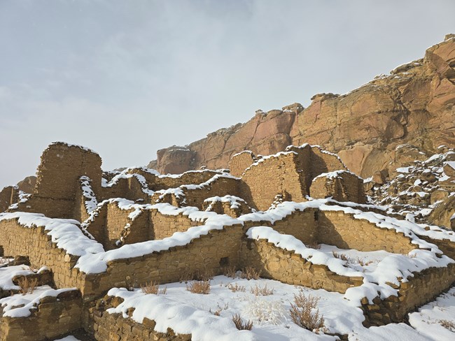 White snow covering the remnants of tan stone walls.
