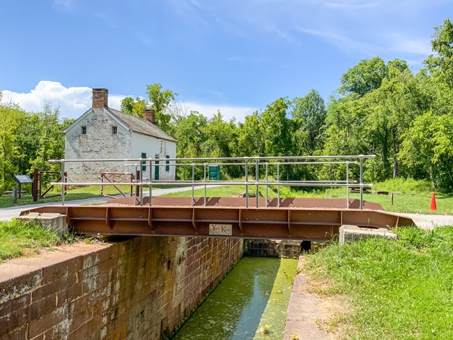 A steel spanner bridge crosses the masonry walls of a lock with water in the canal