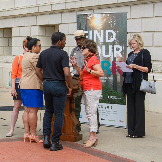 A diverse group of people talking with each other in front of a 