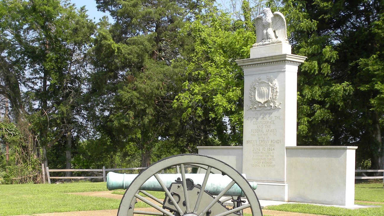 Photo of Brices Cross Roads Battlefield Monument with a civil war cannon placed in front.